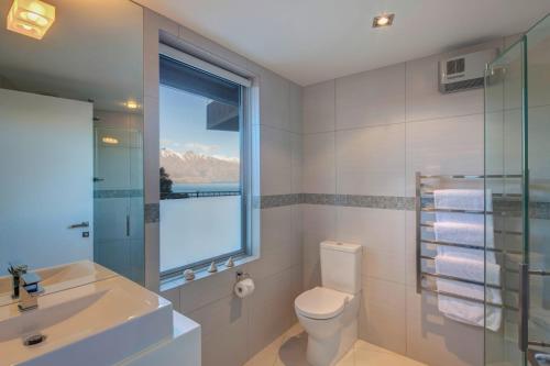 ein Bad mit einem WC, einem Waschbecken und einem Fenster in der Unterkunft Villa Matau- Gas Fire- Lake Views- AC- BBQ in Queenstown