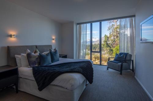 een slaapkamer met een bed en een groot raam bij Villa Pukak-i Gas Fire- Free Parking- Lake Views in Queenstown