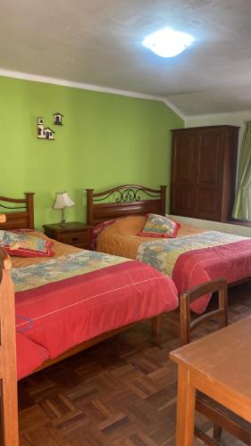 duas camas num quarto com paredes verdes em B&B SANTA CECILIA em Sucre