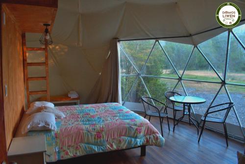 1 dormitorio en una tienda de campaña con 1 cama y 1 mesa en DOMOS LIWEN, en Melipeuco