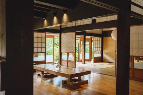 a room with a wooden table and some windows at 古民家の宿Traditional Japanese folk house in Hasunuma