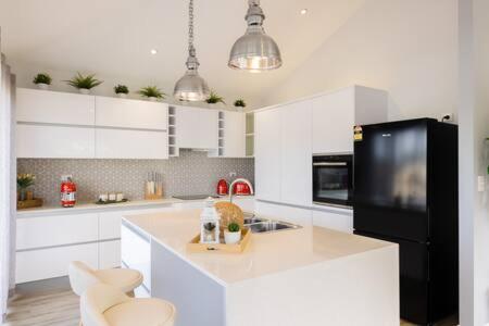 cocina con armarios blancos y nevera negra en An Idyllic Boho Style Retreat High-end kitchenware en Gold Coast