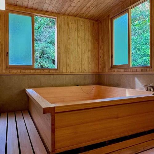 a large wooden bath tub in a room with windows at 古民家の宿Traditional Japanese folk house in Hasunuma