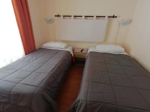 2 letti posti in una piccola camera con riscaldamento a pavimento e riscaldamento a pavimento di Apart Hotel Melipilla a Melipilla
