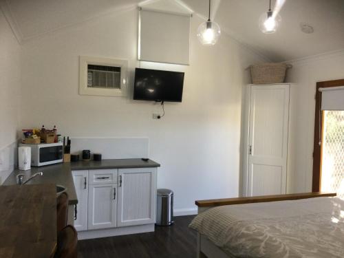 eine Küche mit weißen Schränken und einer Mikrowelle in der Unterkunft Studio on Denne in Tamworth