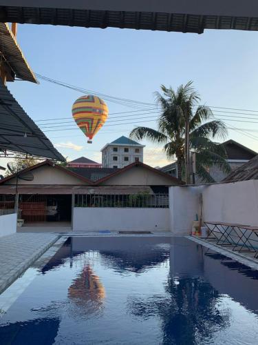 a hot air balloon is flying over a swimming pool at Vang Vieng Global Hostel in Vang Vieng