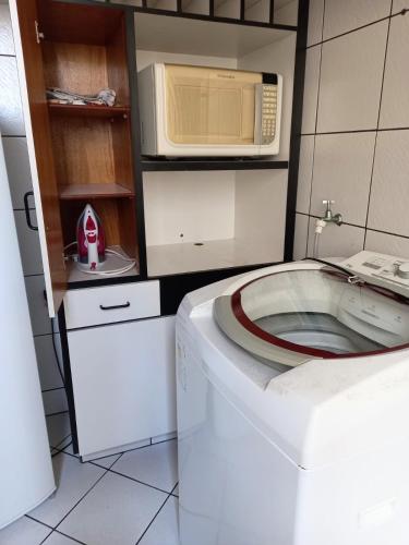 a washing machine in a kitchen with a microwave at Apto 2 Quartos, pertíssimo da Beira-Mar e Ponte HL in Florianópolis
