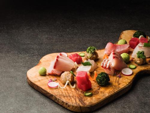 a wooden cutting board with meat and vegetables on it at Grand Mercure Nara Kashihara in Kashihara