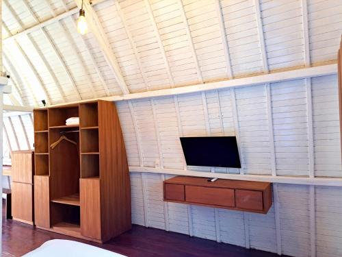 Zimmer mit einem TV an einer Wand und einem Regal in der Unterkunft Wong Village in Tumbak Bayuh