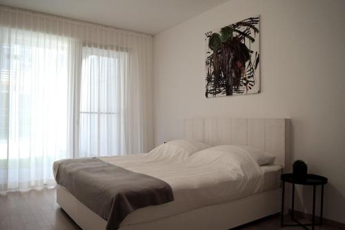 a white bedroom with a bed and a window at Relax Residence Südsteiermark in Ehrenhausen