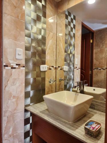 a bathroom with a white sink and a tub at El Mariscal Cusco in Cusco