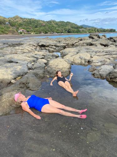 two people laying in the water on a rocky beach at Treetops in Cambutal