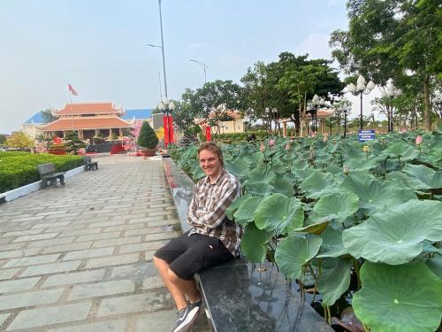 a man sitting on a bench in front of plants at Homestay tay in Xã Trảng Bôm