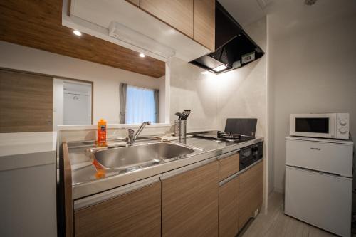 a small kitchen with a sink and a microwave at ASTRAL【2min from Asahikawa sta】 in Asahikawa