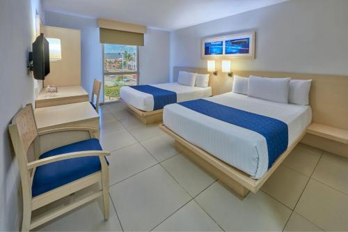 a hotel room with two beds and a chair at City Express by Marriott Manzanillo in Manzanillo