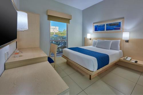a hotel room with a bed and a television at City Express by Marriott Manzanillo in Manzanillo