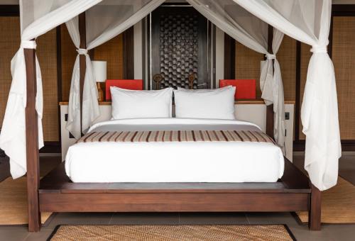 a bedroom with a bed with white sheets and red chairs at Menjaga Bay in Labuan Bajo