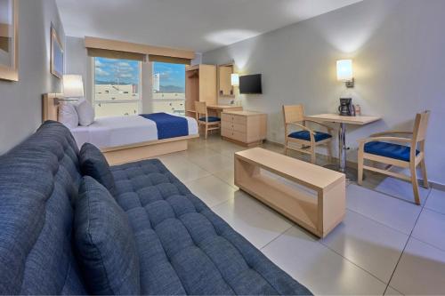 a living room with a couch and a bed and a table at City Express by Marriott Manzanillo in Manzanillo