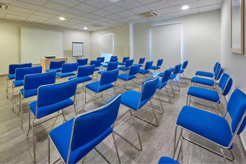 a conference room with blue chairs and a podium at City Express by Marriott Manzanillo in Manzanillo