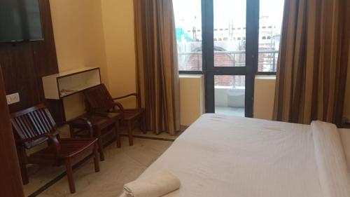 a hotel room with a bed and a chair and a window at HOTEL MERCURY 50 STEP FROM DARBAR SAHIB in Amritsar