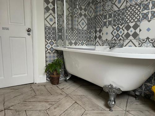 a bathroom with a tub and a tile wall at Ilford Tiny Jewel in Ilford