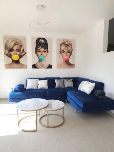 a living room with a blue couch and portraits on the wall at Hermosa casa con vista al lago de Tequesquitengo !! in Tequesquitengo