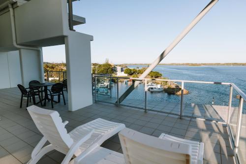 バリナにあるRamada Hotel & Suites by Wyndham Ballina Byronの海の景色を望むバルコニー(椅子付)