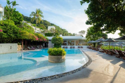 奈漢海灘的住宿－The Nai Harn - SHA Extra Plus，度假村的游泳池,配有椅子和遮阳伞