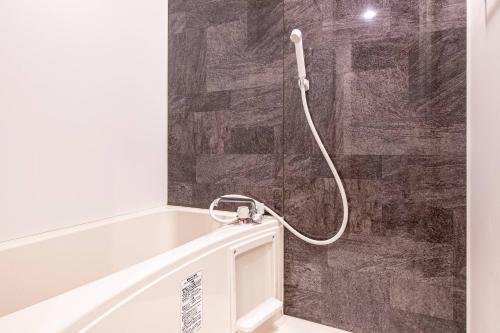a shower with a hose attached to a wall at GRANDE Morisita in Tokyo