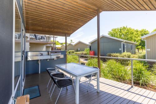 a patio with a table and chairs on a deck at NRMA Batemans Bay Resort in Batemans Bay