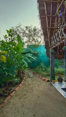 a dirt path next to a building with a blue wall at Open house in Auroville