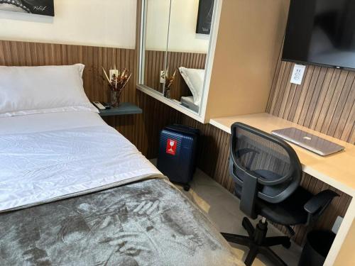 Schlafzimmer mit einem Bett, einem Schreibtisch und einem Stuhl in der Unterkunft Flat Encantador Allianz Park 607 in São Paulo