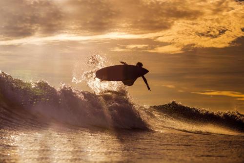 un hombre montando una ola en una tabla de surf en el océano en Hacienda Iguana Surf & Golf apartment, en Tola