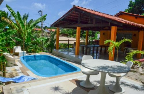 a pool with a table and a chair next to a house at Caçadores de Aventuras Flats in Pipa