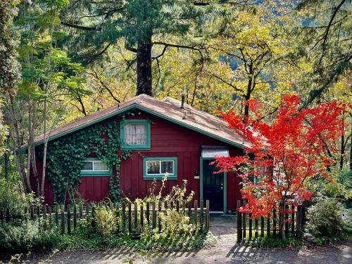 a red house with a fence in front of it at Avenue of the Giants Caraway Cottage (#3) in Miranda