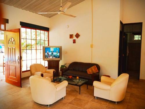 a living room with a couch and chairs and a tv at La Esthera Hospedaje Rural in Carmen de Apicalá