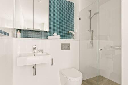 a bathroom with a toilet and a sink and a shower at Coastal 2-Bed Apartment near Beach in Deewhy