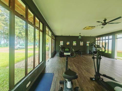 a gym with treadmills and ellipticals in a room with windows at Desaru Black Beach Sky Mirror Resort in Desaru