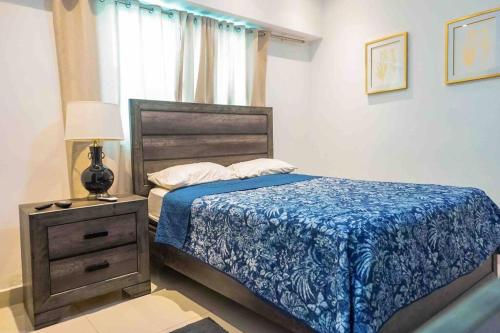 um quarto com uma cama com um edredão azul e uma mesa de cabeceira em Apartment Santo Domingo-Piantini em Santo Domingo