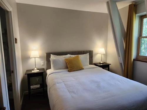 a bedroom with a large white bed with two lamps at Auberge des Nuages in La Malbaie