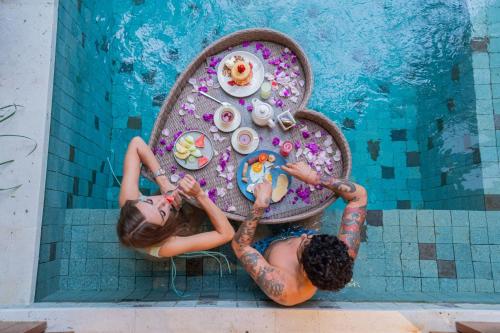 two girls sitting at a table in a swimming pool at The Jimbaran Villa by Ini Vie Hospitality in Jimbaran