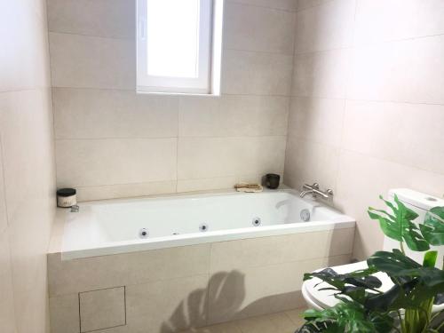 La salle de bains est pourvue d'une baignoire blanche et d'une plante. dans l'établissement Holiday home with private pool in Matacães, à Torres Vedras