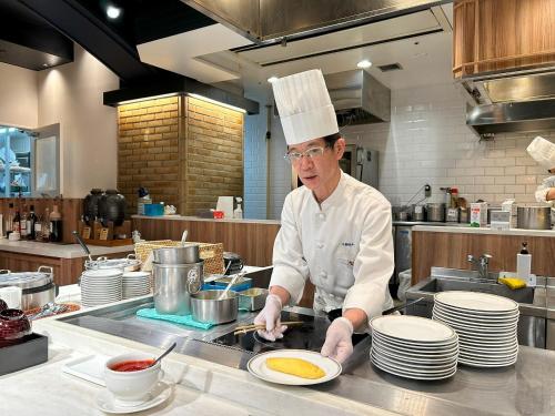 a chef standing in a kitchen preparing food at Garden Hotel Shizuoka in Shizuoka