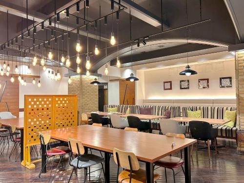 a restaurant with wooden tables and chairs and lights at Garden Hotel Shizuoka in Shizuoka