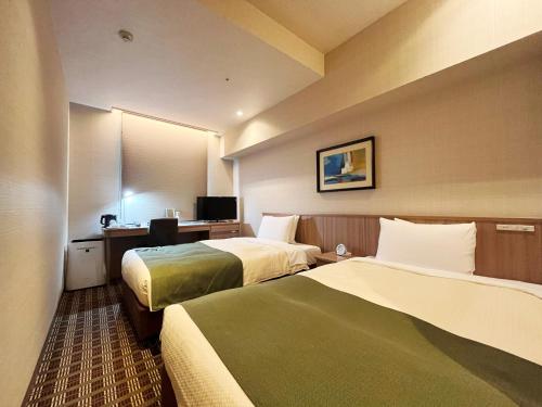 a hotel room with two beds and a desk at Garden Hotel Shizuoka in Shizuoka