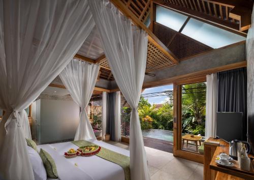 - une chambre dotée d'un lit avec des rideaux blancs dans l'établissement Wana Bucu Villas by Pramana Villas, à Ubud