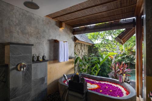 a bathroom with a bath tub with flowers in it at Wana Bucu Villas by GenuineHost in Ubud