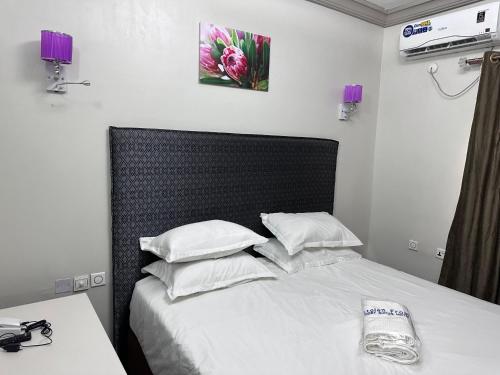 1 dormitorio con 1 cama con sábanas y almohadas blancas en Crest Suite and Lifestyle, en Owerri