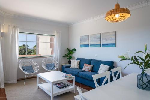 TAC - Serene Shores - Portimão في Vau: غرفة معيشة مع أريكة زرقاء وطاولة