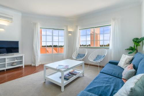 TAC - Serene Shores - Portimão في Vau: غرفة معيشة مع أريكة زرقاء ونافذتين